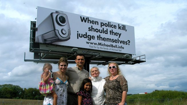 Michael Bell Sr. (center) and his family stand near one of the billboards they bought in a campaign to bring awareness to internal police investigations. Bell's son was shot and killed by police in Kenosha, Wis.